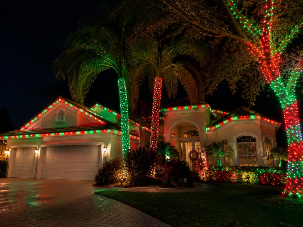 Florida home with palm trees showing permanent roofline lighting in classic Christmas red and green